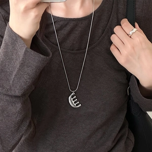 Minimalist silver comb pendant necklace and wavy ring set on a knit sweater background
