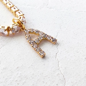 Macro shot of gold letter A pendant with clear zircon inlay on a tennis chain