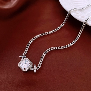 Détail du collier pendentif zircon carré avec breloques croix sur de la soie rouge