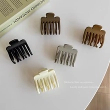 Five Morandi matte claw clips in black, brown and cream on a minimalist background
