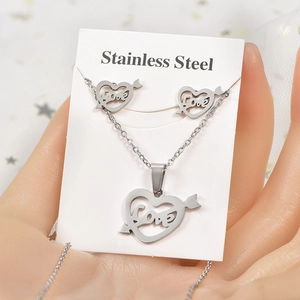 Detailed view of silver stainless steel heart and arrow jewelry set held in hand