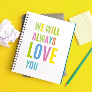 Top view of yellow spiral grid notebook with colorful art lettering and pencils