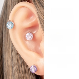 Detailed view of star-shaped cartilage earrings featuring blue, pink and purple zircons