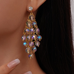 Macro view of gold crystal rhombus dangle earrings worn by a model in close-up shot