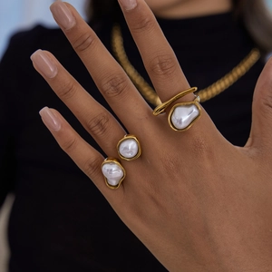 Close-up of baroque pearl rings on fingers featuring golden stainless steel bands