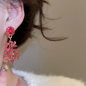 Macro shot of festive red and gold Chinese character joy drop earrings on a model