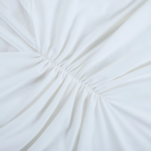 Detailed view of white pleated evening dress showing mesh stitching and silky fabric texture