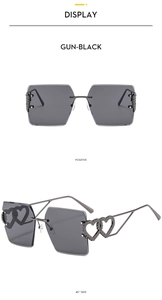 Detail of gun-black rimless square sunglasses featuring hollow heart-shaped metal temples