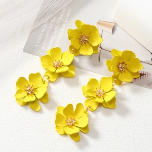 Vibrant yellow flower earrings with multilayered petals and gold accents on white background