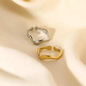 Dettaglio macro di anelli aperti ondulati in oro e argento su tessuto di seta