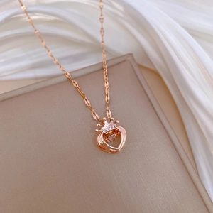 Detail of rose gold crown heart necklace with crystals on soft silk background