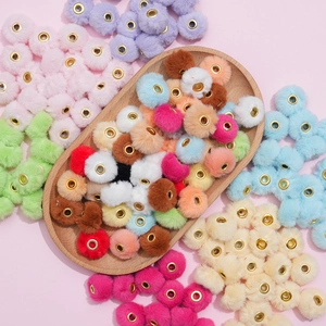 Close-up of 20mm colorful faux rabbit fur pompom beads with golden metal eyelets for DIY