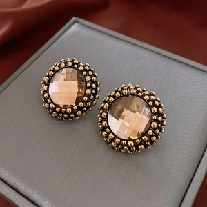 Macro detail of vintage floral earrings with amber gems and bronze beaded texture