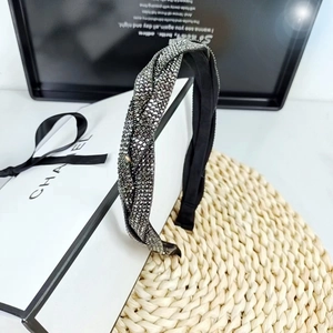 Braided wide headband with dark rhinestones on a decorative box and straw mat