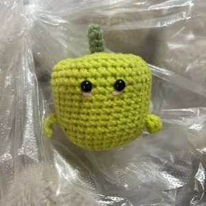 Macro shot of handcrafted green crochet monster toy in protective plastic packaging
