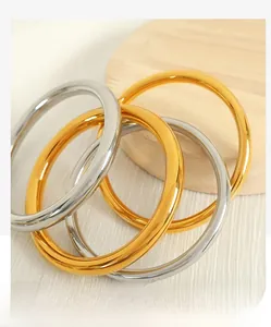 Polished gold and silver minimalist bangles displayed on a rustic wooden tray