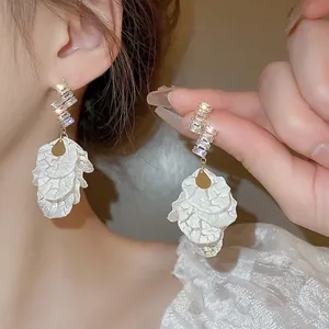 Détail des boucles d'oreilles pétales de perle avec clous dorés en zircon