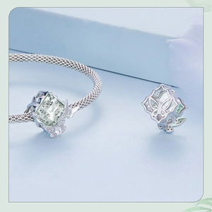Macro detail of silver butterfly bead with green gemstone and zircon insets