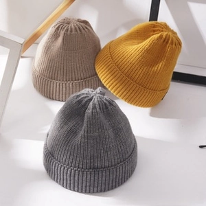 Flat lay of ribbed knit beanies in grey, yellow, and beige for autumn and winter wear