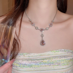 Dettaglio di collana d'argento con cristallo rosa a goccia indossata da una modella