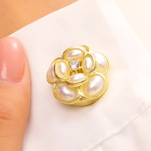 Gros plan d'une boucle de vêtement camélia avec perles blanches et bordure dorée
