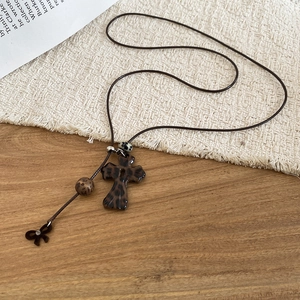 Détail du collier croix avec motif léopard, breloque nœud et cordon marron foncé