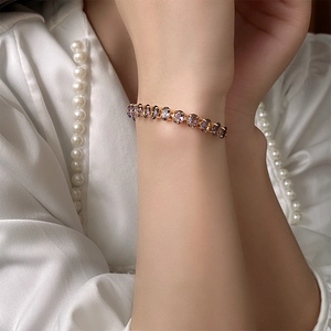 Detailed close-up of gold zircon bracelet featuring purple oval gemstones on female wrist