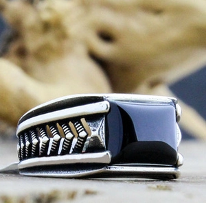 Macro shot of men's vintage silver ring featuring a square black gemstone and arrow pattern