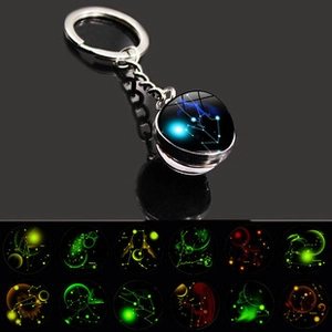Detailed macro view of glow-in-the-dark glass dome zodiac keychains in various designs
