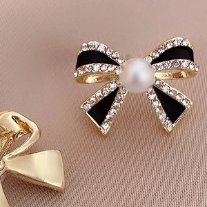 Macro view of vintage bow earring with black enamel, rhinestones and pearl detail