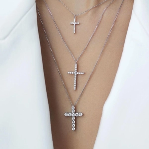 Close-up of three layered silver cross necklaces with zircon inlays on a model
