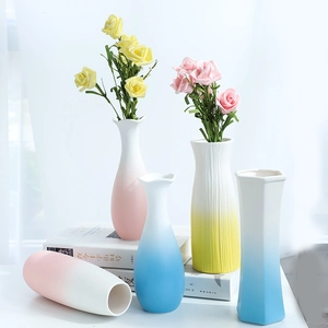 Modern gradient ceramic vases with matte finish and artificial roses on white books
