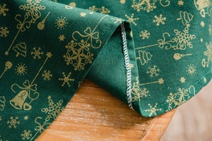 Detailed macro view of green Christmas tablecloth with gold snowflake and bell prints
