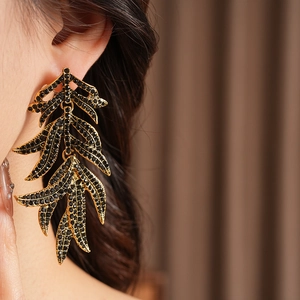 Detail of vintage gold leaf earrings with black rhinestones worn by a model