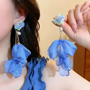 Detail of blue tulle petal drop earrings with floral beads and long golden metal bar