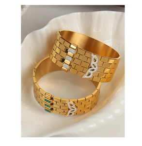 Detail of 18K gold plated titanium bangles with emerald gems and diamonds in a ceramic dish