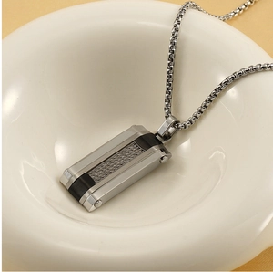 Close-up of a silver hip-hop rectangular pendant with woven steel cable and black details