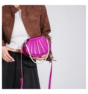 Detail der muschelförmigen Umhängetasche in Metallic-Magenta mit Perlenkette
