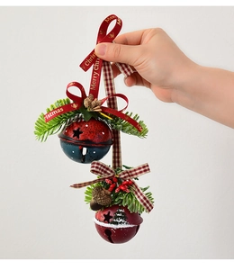 Close-up of Christmas bells with pine cones, red berries and Merry Christmas ribbon