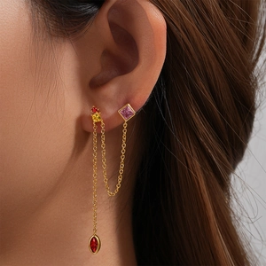 Close-up of golden tassel chain earring with colorful zircon stones on model's ear