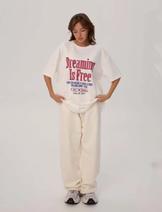 Dettaglio della t-shirt oversize in cotone bianco con stampa Dreaming Is Free sul petto