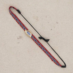 Detail of hand-woven geometric bracelet with blue evil eye charm and adjustable cord