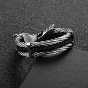 Macro detail of braided steel cable bracelet featuring intricate wolf head metal clasps