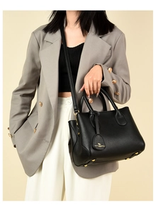 Detail of black pebbled leather tote bag styled with grey suit for professional commute