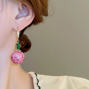 Detail of retro pink ceramic drop earring with green beads worn on ear for women