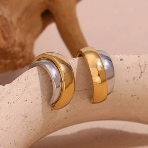 Macro detail of wide C-shaped mixed gold and silver plated stainless steel earrings