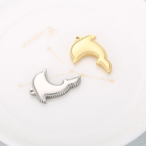 Polished dolphin pendants in gold and silver steel finish displayed on a ceramic plate