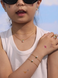 Girl wearing cute golden crown jewelry set with white pearls and green leaf charms