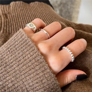 Close-up of S925 sterling silver ring set featuring a smiley face and minimalist bands