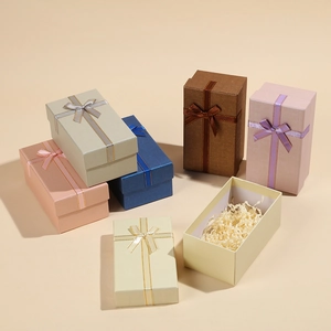 Various colored luxury jewelry gift boxes with silk bows and paper filler on beige background